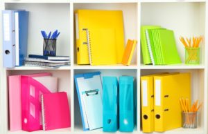 Colorful and organized notebooks, binders and office materials in a bookcase